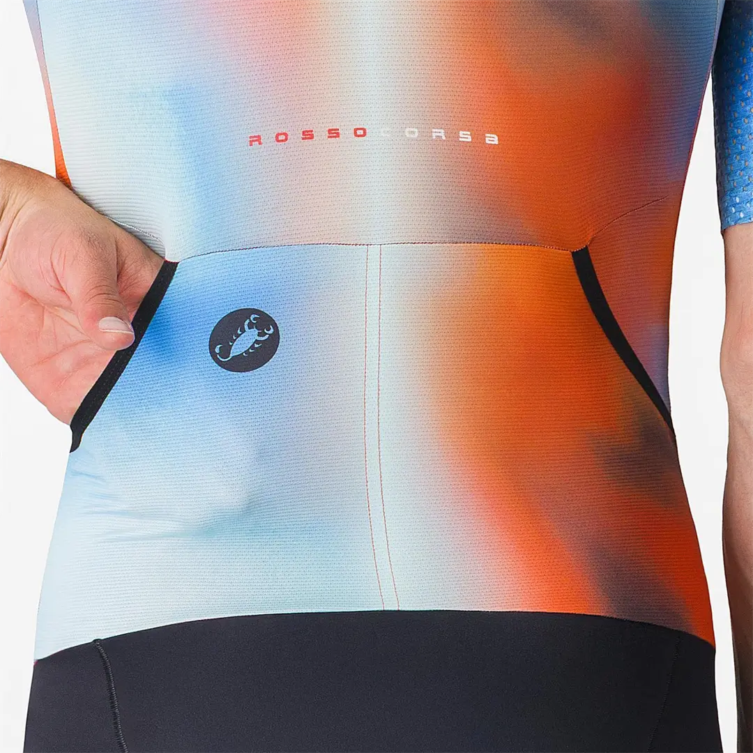 Dłoń sięga do jednej z dwóch kieszonek koszulki stroju triathlonowego z logo skorpiona.